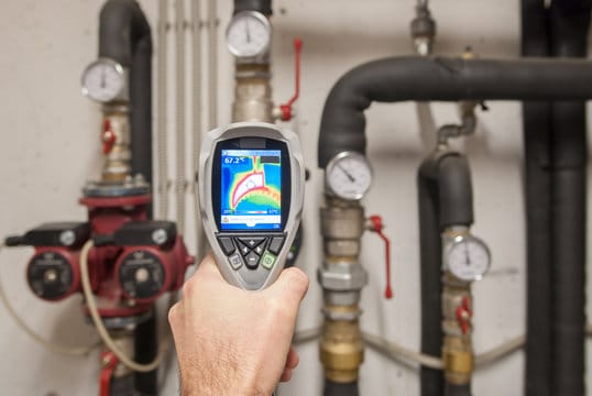 Plumber using a thermal imaging camera to inspect pipes in Beaumont